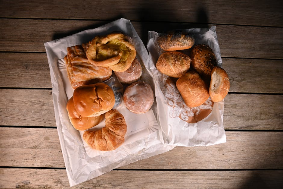 Top view of a variety of freshly baked bread and pastries on a wooden table, illustrating a bakery's diverse offerings.