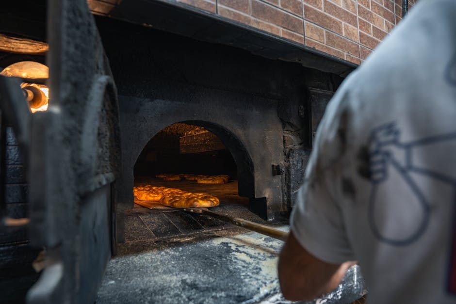 Baker tending to loaves in a traditional brick oven captures the essence of artisanal baking.