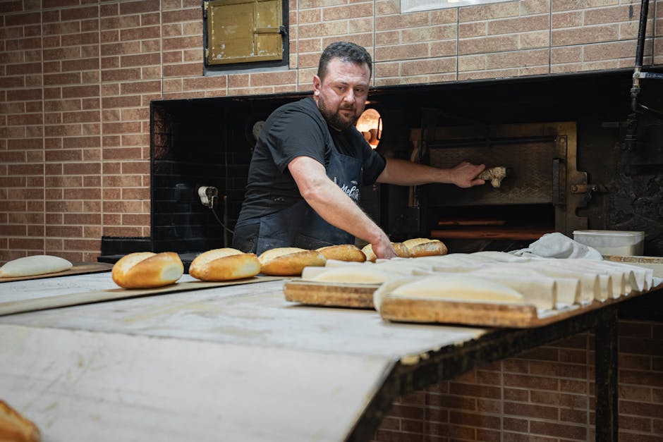 Experienced artisan baker working in a traditional bakery, baking fresh bread daily.